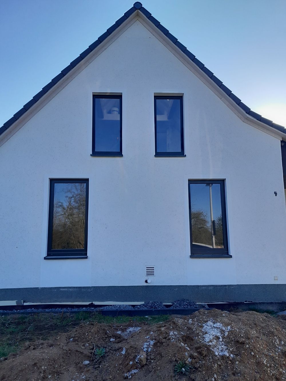 Weißes Haus mit vier dunklen Kunststofffenstern